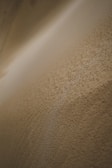 Close-up of a sand-colored textured surface with subtle light gradients.