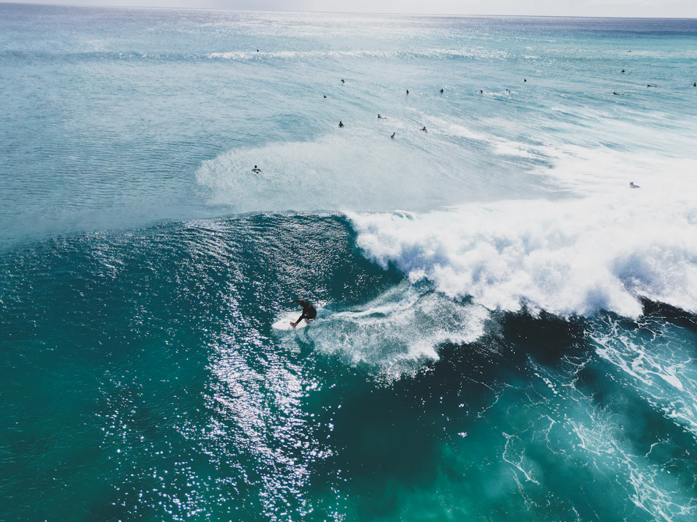 A surfer riding a turquoise wave off Fuerteventura, with others waiting out the back