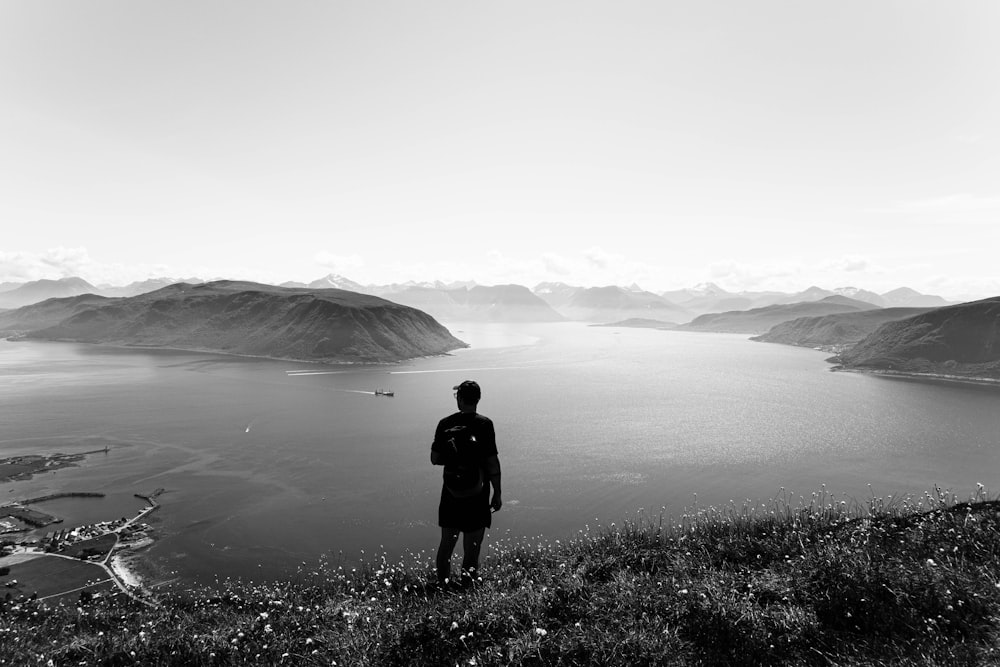 a man standing on top of a hill next to a lake