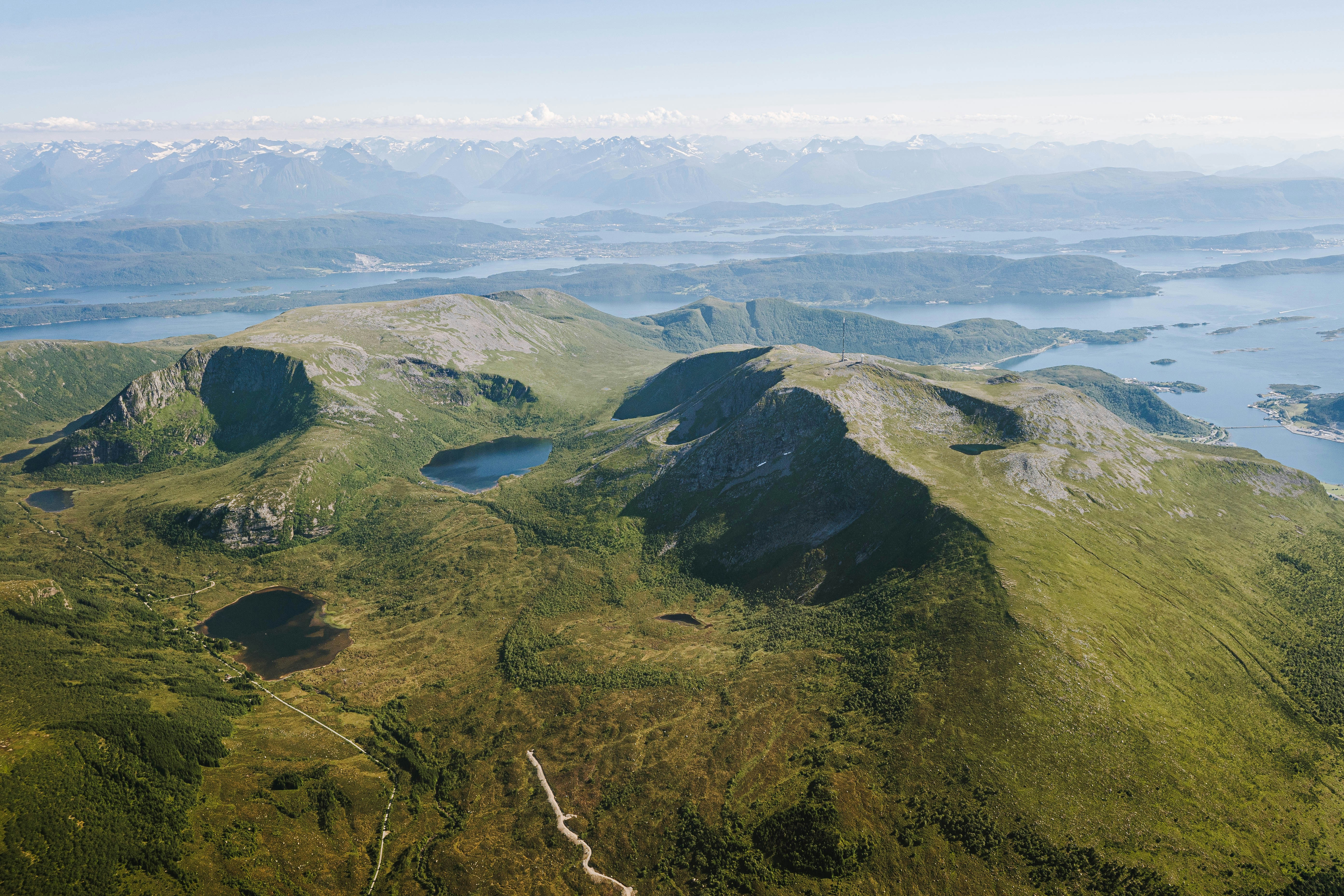 an aerial view of a mountain range with a body of water in the distance, 