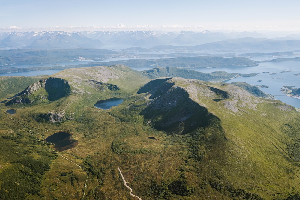 an aerial view of a mountain range with a body of water in the distance