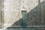 Rustic wooden door with intricate carvings set against a stone wall.