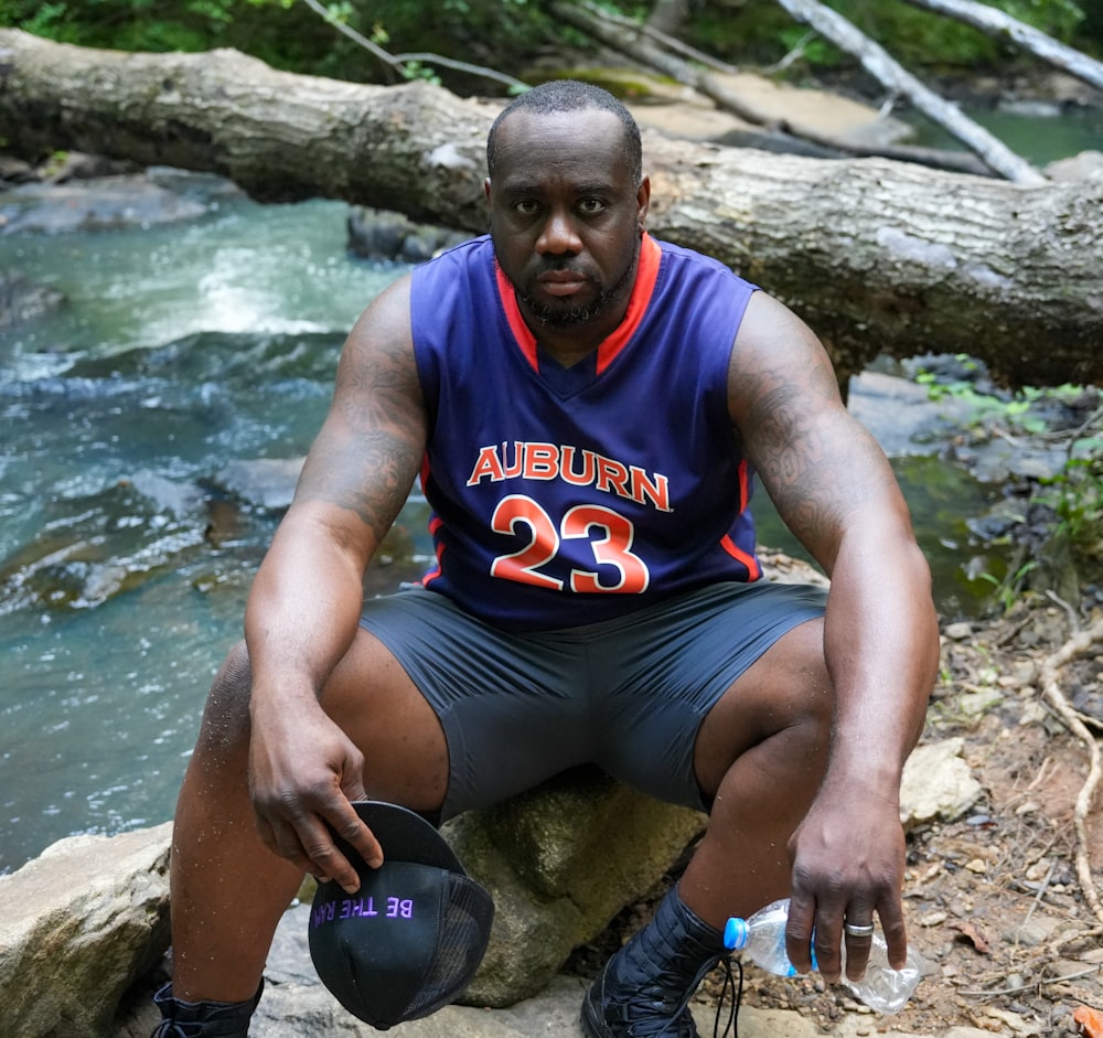 a man sitting on a rock next to a river