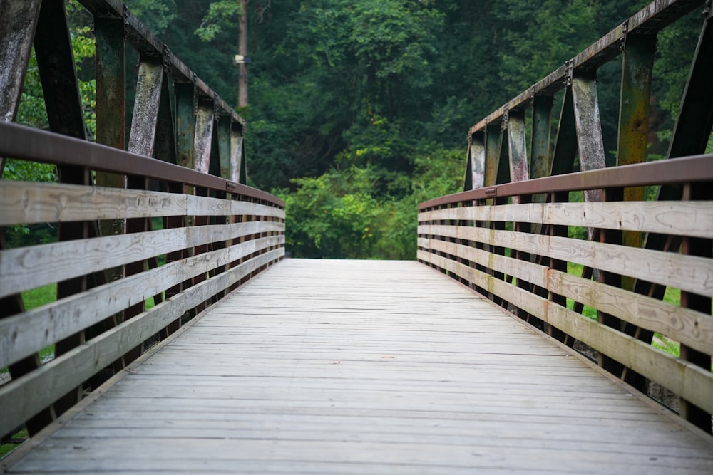 a wooden bridge over a river with trees in the background