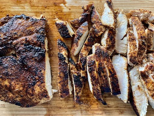 a wooden cutting board topped with sliced up meat