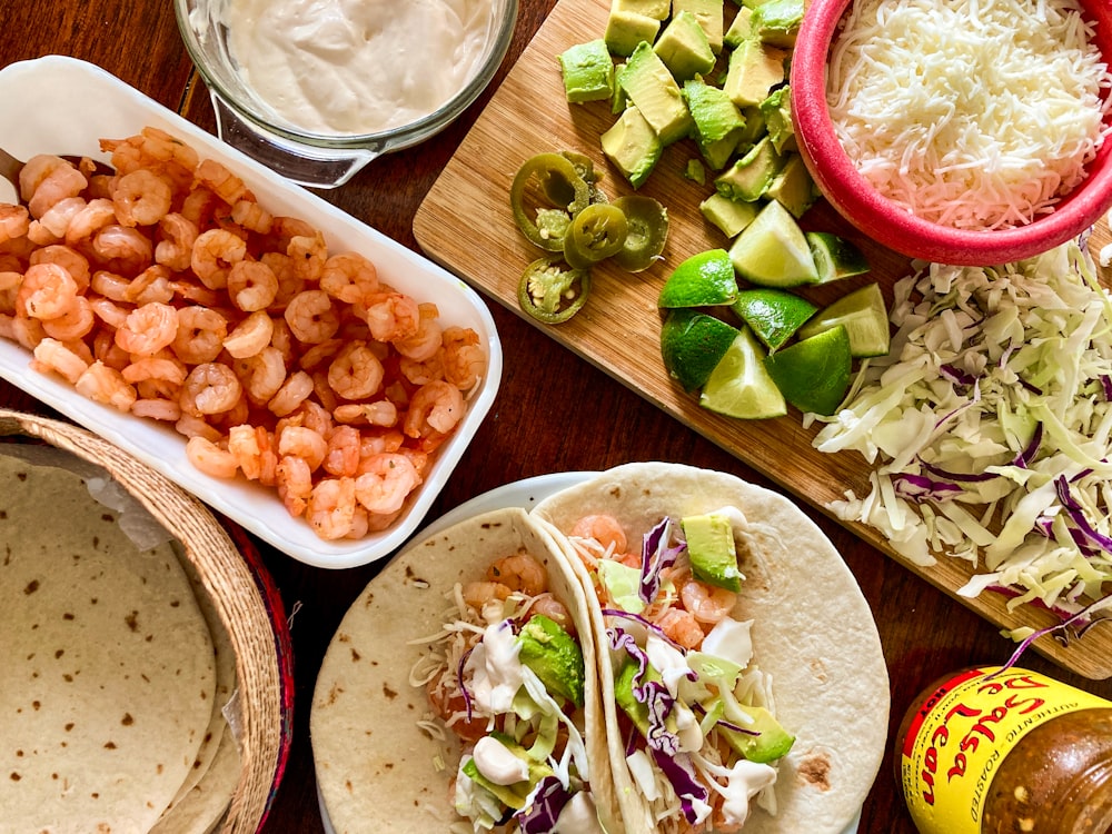 a table topped with tacos, guacamole and other foods