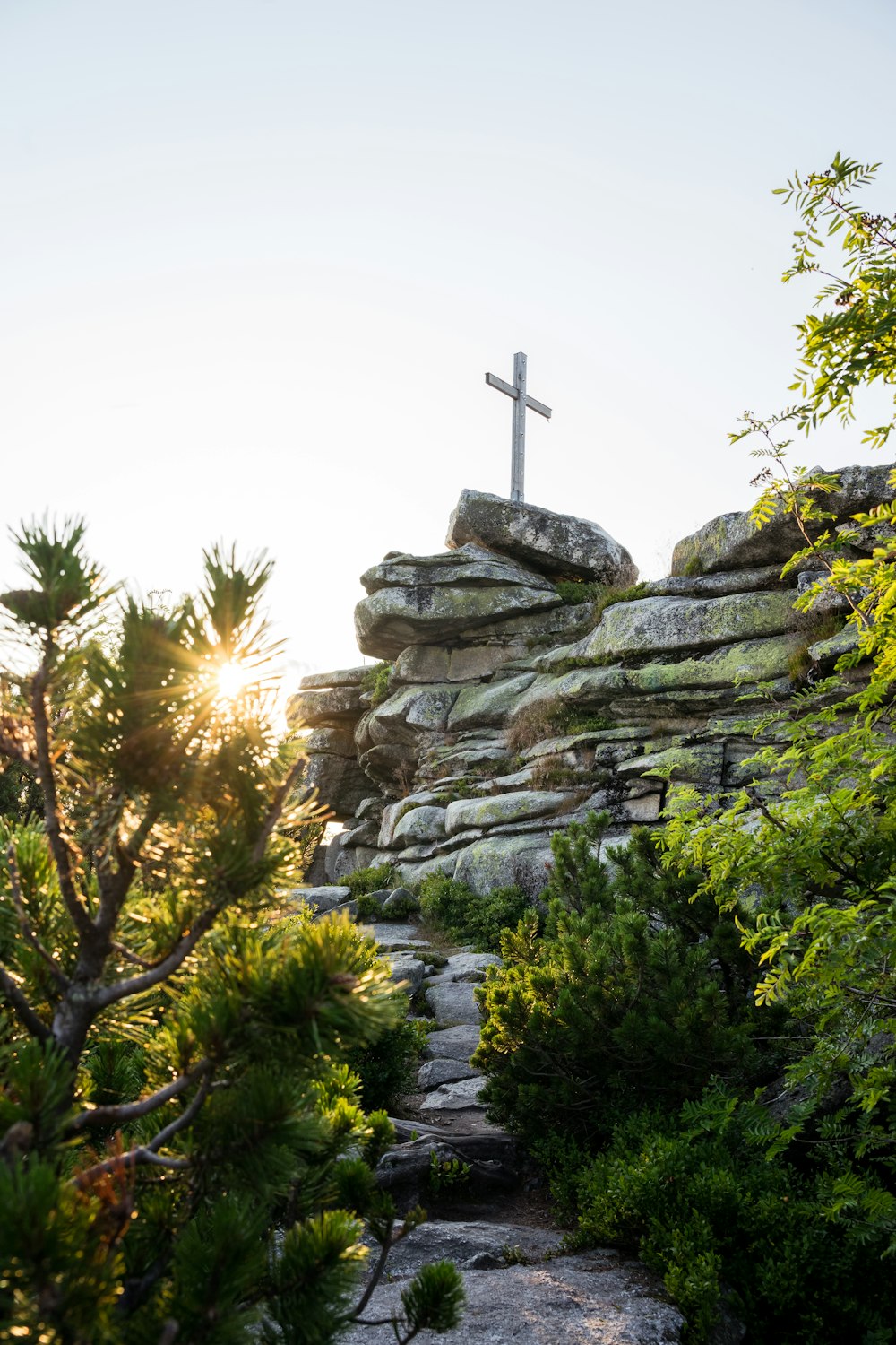 a cross sitting on top of a rocky hill