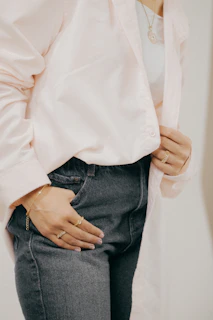 A casual outfit featuring a light blouse and jeans, paired with subtle gold jewelry, perfect for everyday charm.