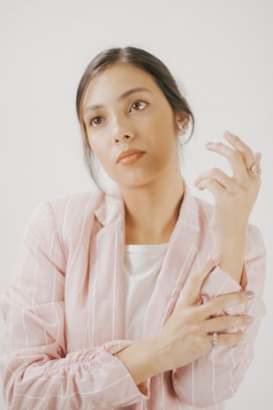 A smiling woman in a soft pink sweater, deep in thought while brainstorming ideas.