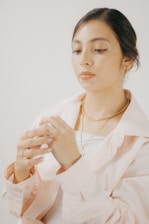 Woman wearing delicate earrings and necklace in natural light.