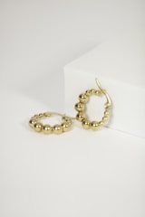 a pair of gold hoop earrings on a white surface