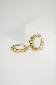 a pair of gold hoop earrings on a white surface