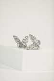 Two intricately designed butterfly-shaped earrings encrusted with small gemstones, placed on a white, minimalist platform. The earrings have a delicate and detailed appearance, with the light reflecting off their shiny surfaces.
