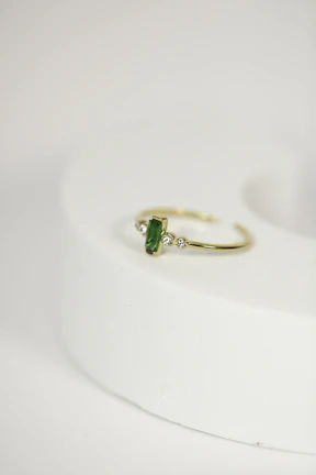 Close-up of a gold ring with a deep green emerald, sparkling under soft light.