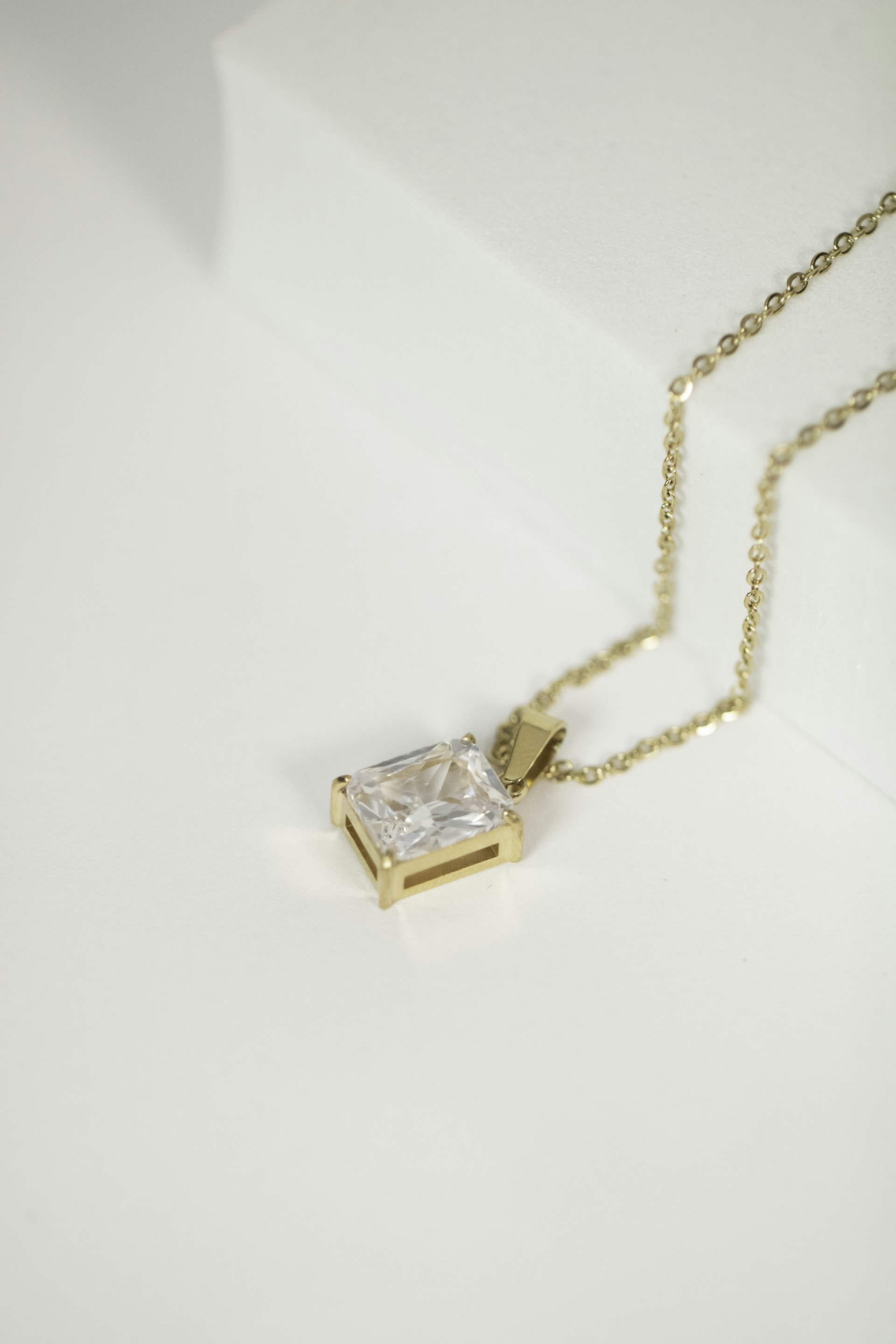 a necklace with a square cut diamond on a chain