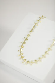 A collection of layered gold necklaces displayed on a wooden jewelry stand.