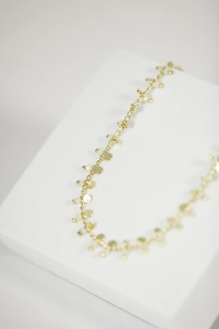 Delicate 18k gold necklaces with unique pendants displayed on a rustic wooden table.