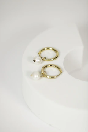 Elegant earrings displayed on a minimalist white pedestal with natural sunlight streaming in.