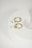 Two gold hoop earrings with white pearl pendants are placed on a white, curved, hollow object. The setup has a minimalist and elegant aesthetic.