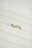 A gold ring with a twisted design, encrusted with small diamonds, placed on a white textured surface.