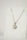A joyful woman admiring her delicate heart-shaped zirconia necklace in natural light.