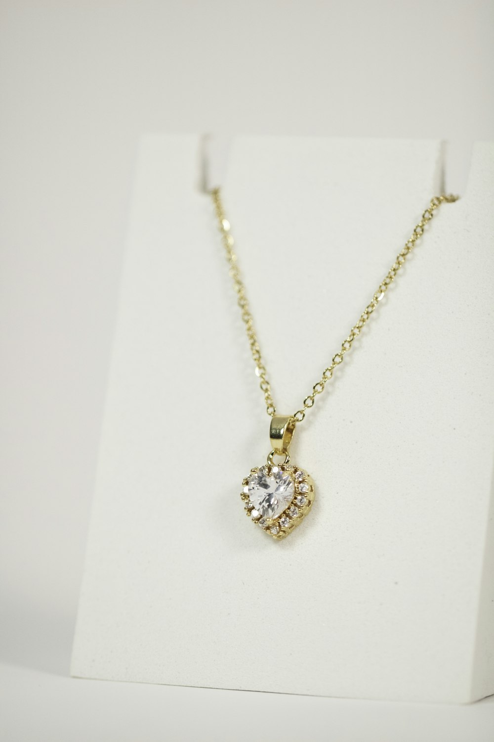 a gold necklace with a white diamond on it