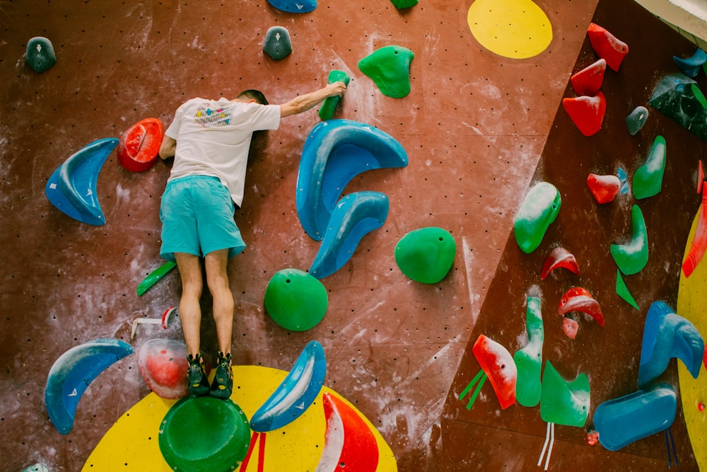 a young man is climbing on a climbing wall
