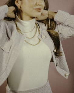 A cozy knit sweater layered over a chic skirt, accessorized with delicate gold jewelry for a polished look.