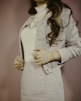 A casual outfit featuring a soft knit sweater and tailored trousers, styled with delicate gold jewelry.