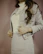 Close-up of a joyful woman in an elegant cream white suit with warm brown accents.