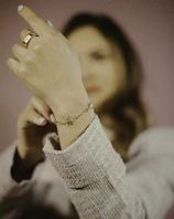 Lifestyle shot of layered bracelets on a wrist resting on a champagne gold silk fabric.