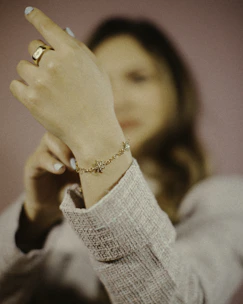 Delicate charm bracelets layered on a wrist, styled with casual streetwear in an urban outdoor setting.