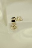 Elegant jewelry pieces featuring intricate designs with pearls and gold accents are displayed against a soft, textured background. The jewelry includes earrings that combine black stones and clusters of pearls with shiny embellishments.