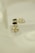 Elegant jewelry pieces featuring intricate designs with pearls and gold accents are displayed against a soft, textured background. The jewelry includes earrings that combine black stones and clusters of pearls with shiny embellishments.