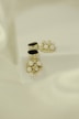 Elegant jewelry pieces featuring intricate designs with pearls and gold accents are displayed against a soft, textured background. The jewelry includes earrings that combine black stones and clusters of pearls with shiny embellishments.