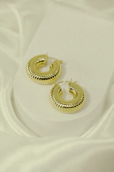 Elegant pair of gold hoop earrings resting on a marble surface with natural light