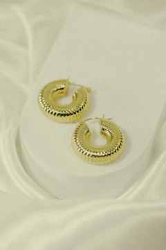 Close-up of delicate gold hoop earrings on a black velvet surface.