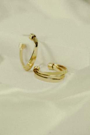 Elegant pair of gold hoop earrings resting on a rustic wooden surface