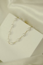 A close-up of a delicate necklace displayed elegantly on a soft fabric background.