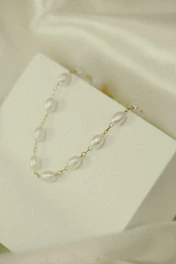 Elegant gold necklace with a minimalist pendant displayed against a deep black background with subtle reflections.