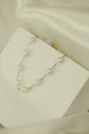 Elegant beaded necklaces layered on a minimalist white background showing varied bead sizes and colors