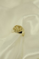 Close-up of a delicately crafted silver ring resting on soft white silk.