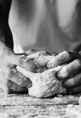 Black and white styled photo of a baker’s hands shaping dough.