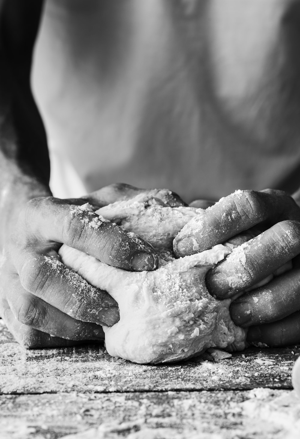 a black and white photo of a person kneading dough