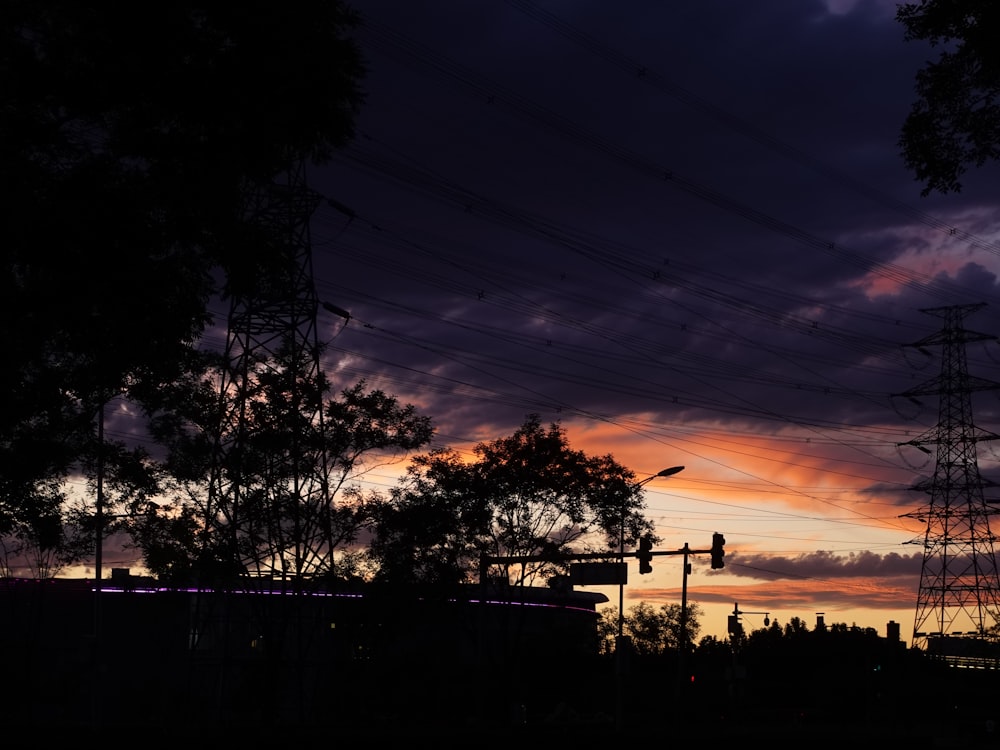a sunset with power lines and trees in the foreground