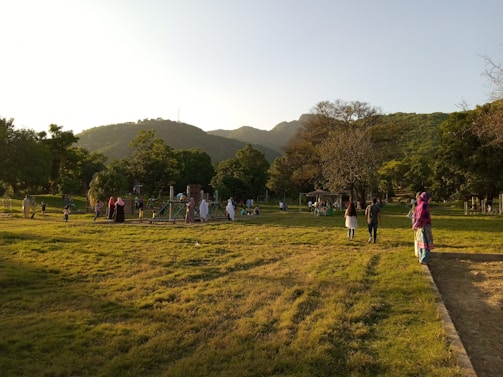 A charming neighborhood park with children playing and neighbors chatting on benches in the late afternoon.