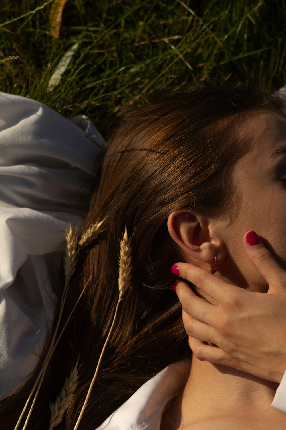 a woman laying in the grass with her hands on her face