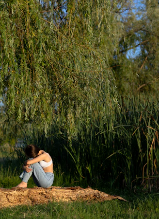 a woman sitting on a log under a tree