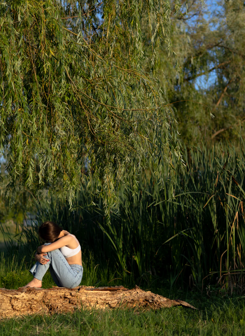 a woman sitting on a log under a tree