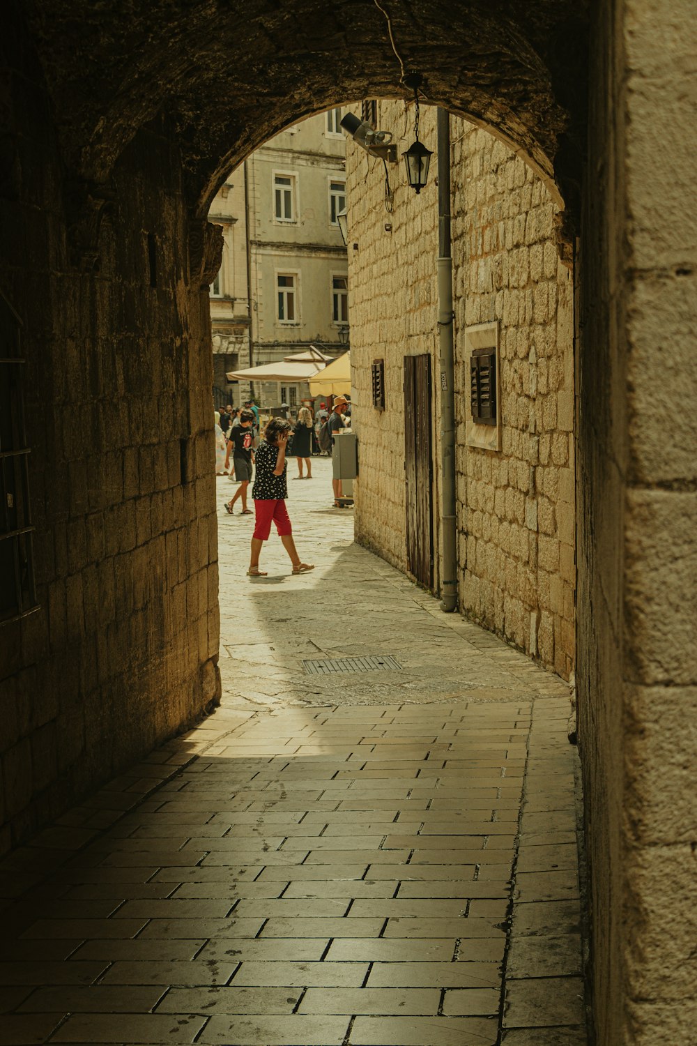 a person walking down a street under an archway
